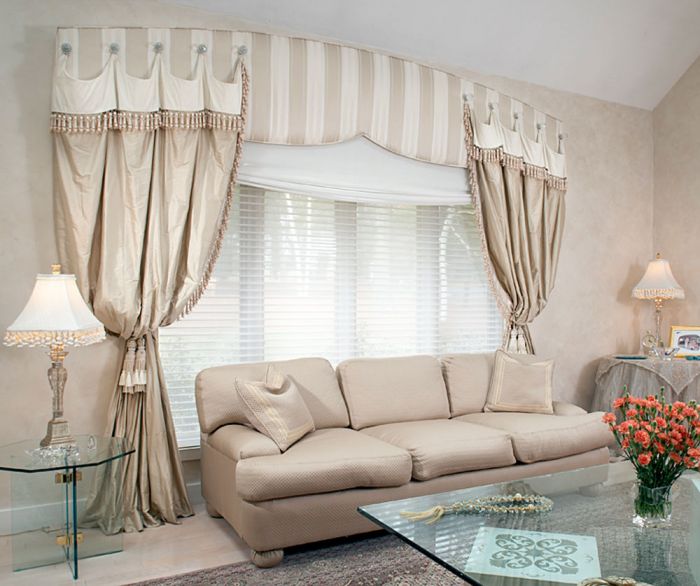 A living room with a beige couch and unique drapery.