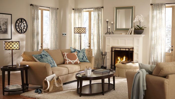 A dreamy living room with cozy beige furniture and a charming fireplace.