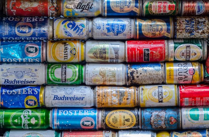 Many beer cans are stacked together in a row to facilitate recycling.