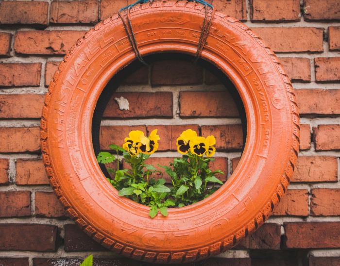 A guide to repurposing a tire as a planter on a brick wall.