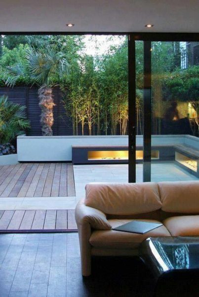 A modern living room with sliding glass doors and a wooden deck in a backyard patio.