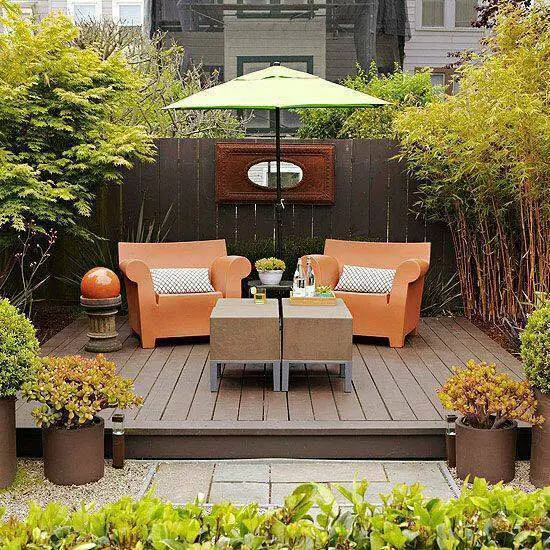 A small patio with orange furniture and an umbrella.