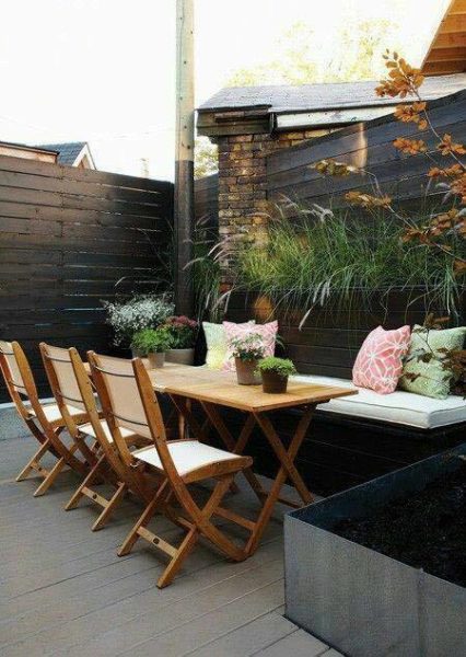 A wooden table and chairs on a small backyard patio.