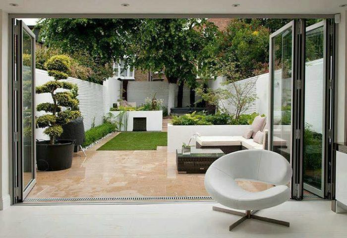 A white backyard patio with a small garden.