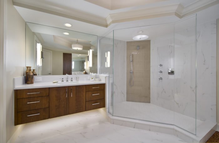A luxurious spa bathroom with a glass shower stall and marble counter tops.