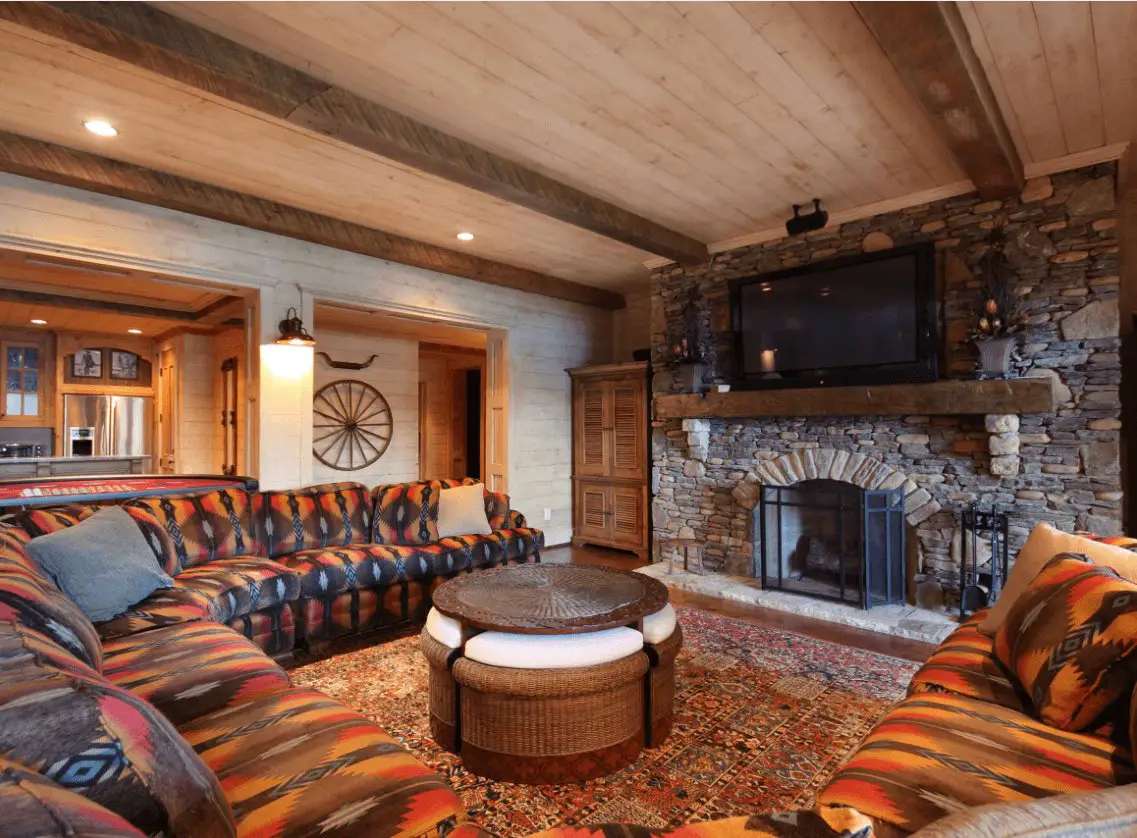Cozy rustic living room with stone fireplace and patterned sofa.