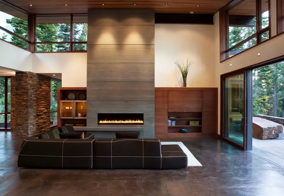 Modern living room with fireplace and forest view.