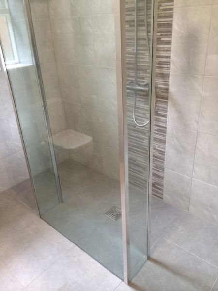A DIY bathroom remodel with a glass shower stall and tiled floor.