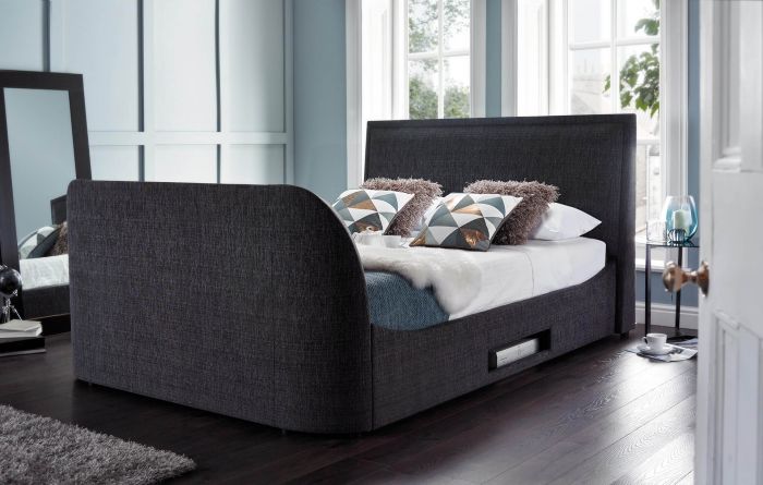 A bed with a slatted base in a bedroom that can also accommodate a TV.