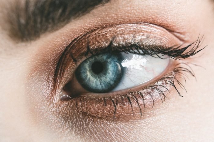 A close up of a woman's blue eye with eyelash extensions.