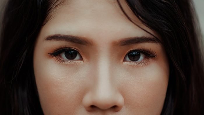 A close up of a woman with brown eyes enhanced by eyelash extensions.