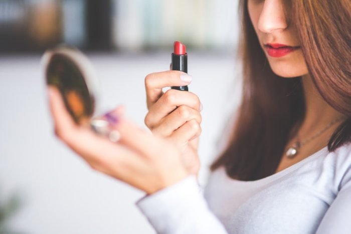 A woman is applying lipstick at a beauty counter.