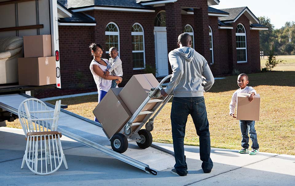 A man encountering moving problems while transferring boxes from a moving truck with his family.