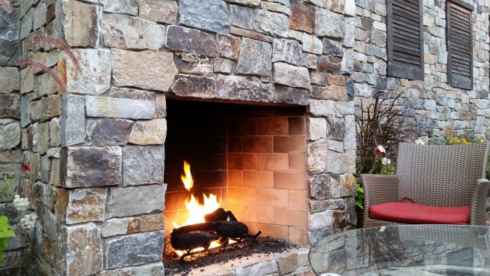 Decorate a patio with a stone fireplace and table.