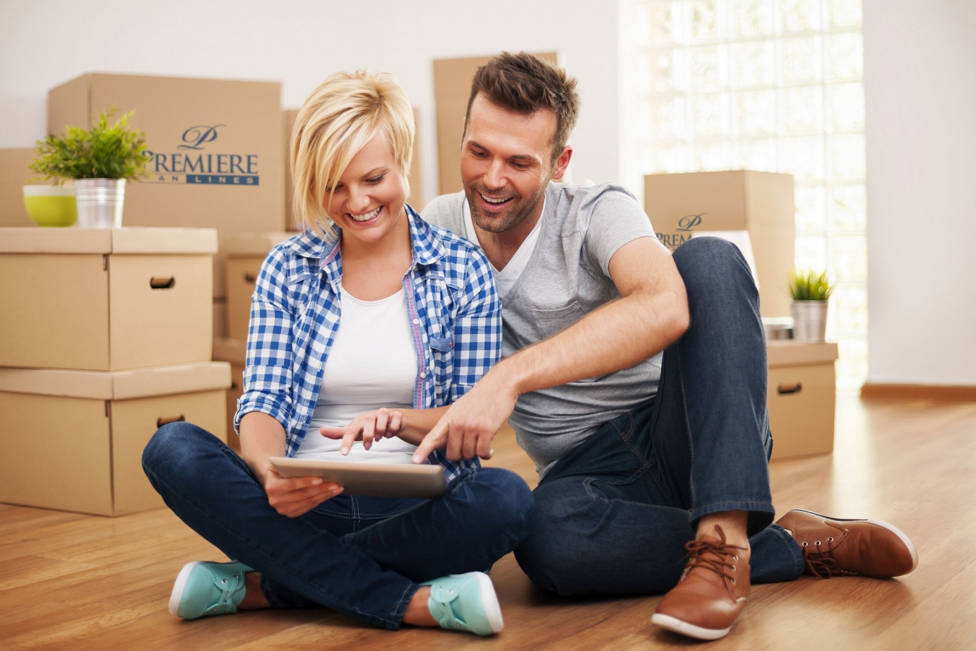 A couple sitting on the floor surrounded by moving boxes during a house relocation.