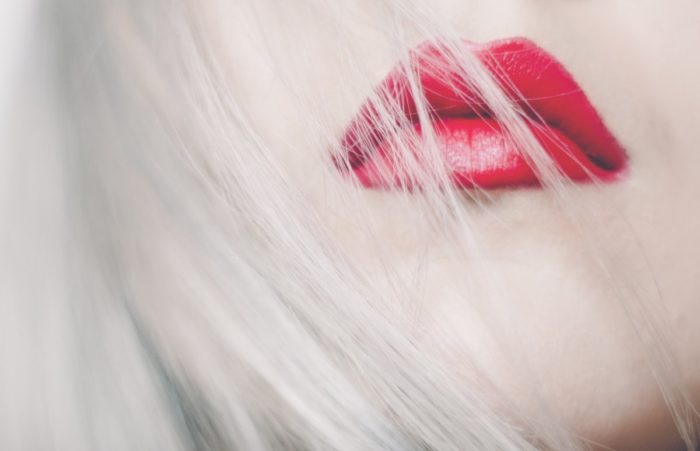 A close up of a woman with red lips wearing red lipstick.