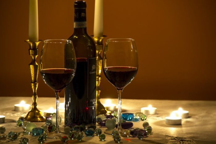 Two glasses of wine and candles on a table.