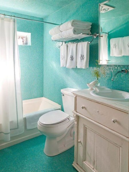 A design bathroom with turquoise tile floors and a white toilet.