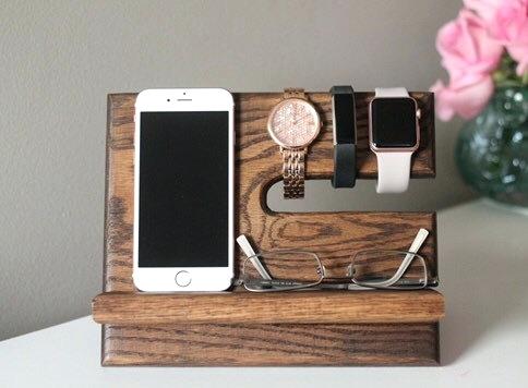 A wooden phone holder with a watch and phone, ideal for furniture.