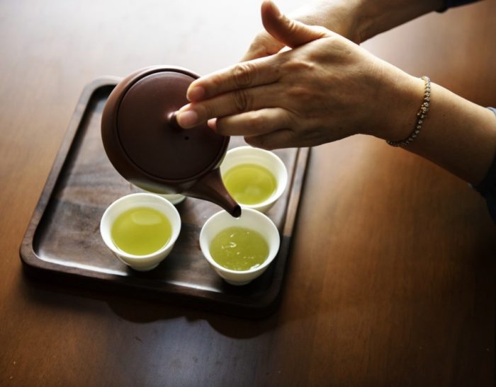 A person pouring green tea for glowing skin.