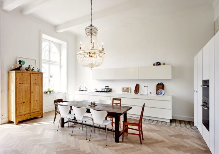 A white kitchen with wooden floors and a chandelier, perfect for a budget-conscious homeowner.