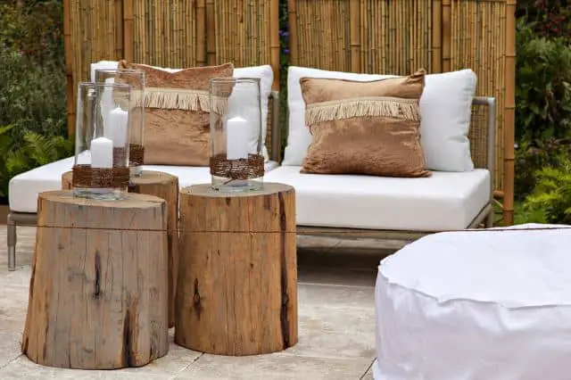 A budget-friendly outdoor garden featuring a white couch and two wooden stumps.