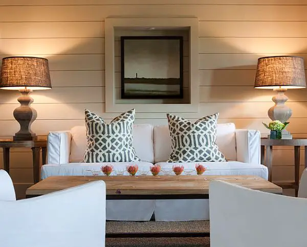A living room designed with two white couches and two lamps.