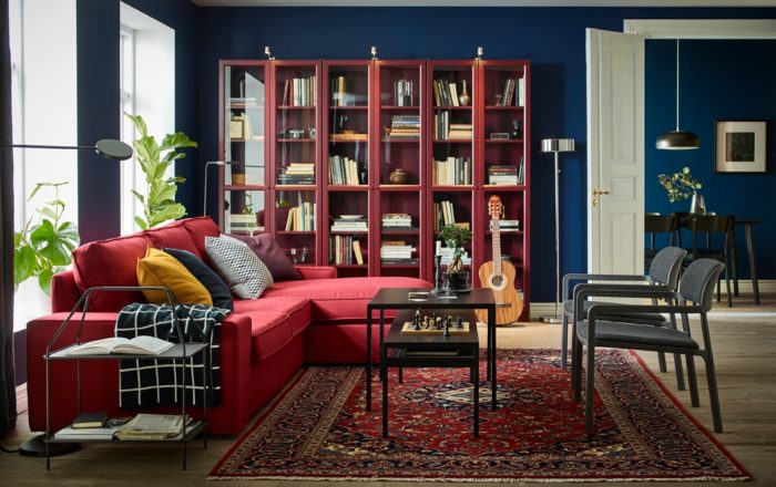 A cozy living room with vibrant red furniture and bookshelves.