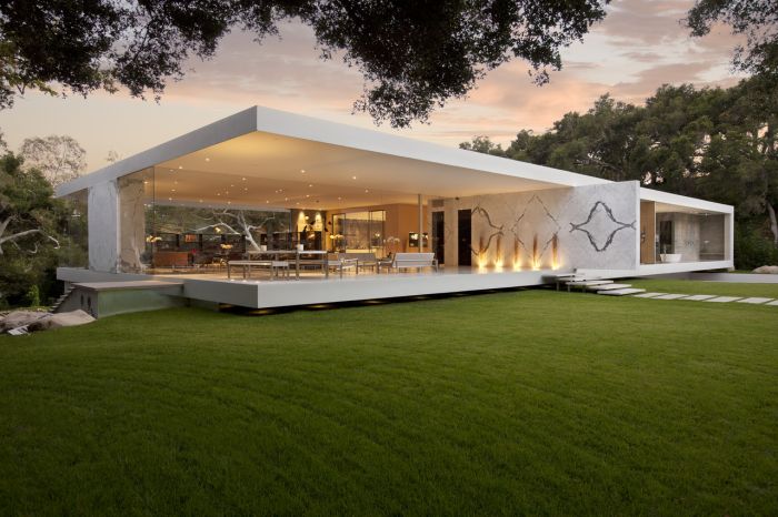 A minimalist modern house in the middle of a green lawn.