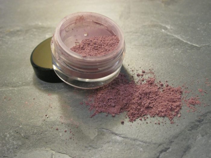 A jar of pink eyeshadow on a marble surface, perfect for a touch of blush.