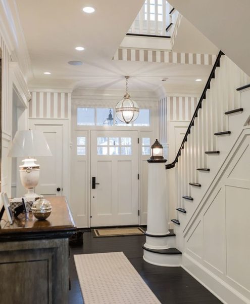 A white and black lighthouse home with a staircase in the foyer.
