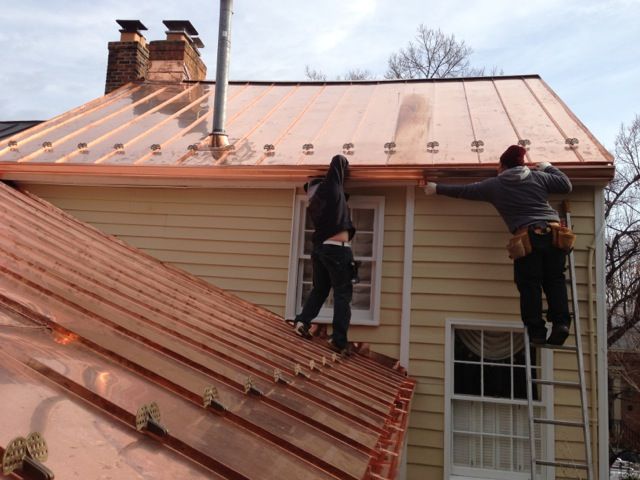Two men experimenting with unconventional roofing ideas on a copper roof.