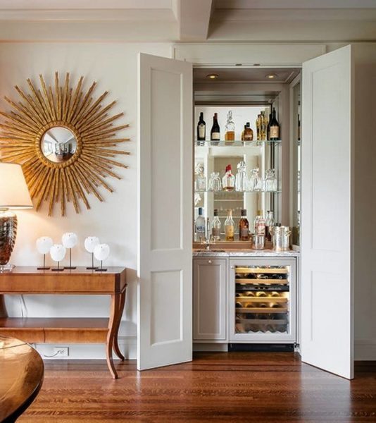 A living room with a creative wine bar and a large mirror.