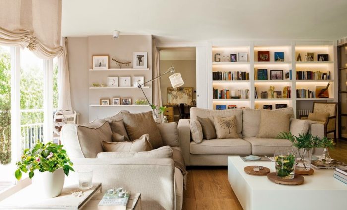 A cozy living room with white furniture and bookshelves.