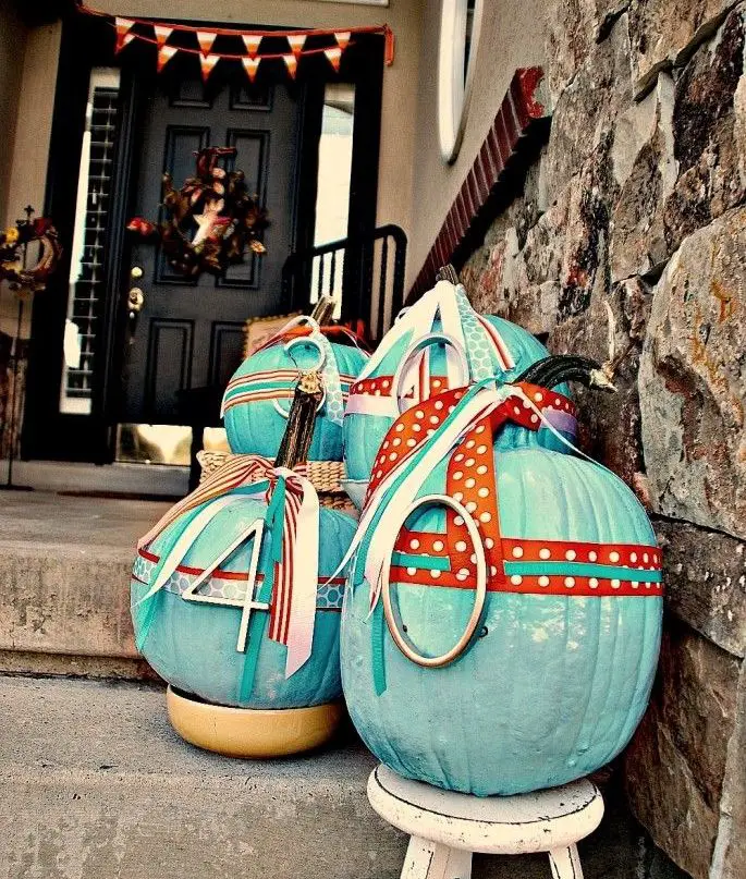 Turquoise pumpkins decorated as Easter eggs on porch.