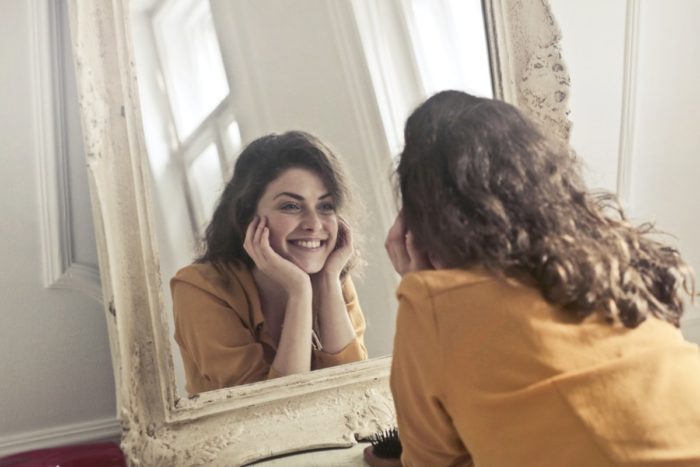 A woman is examining her dark circles in a mirror.