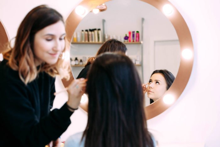 A woman getting her makeup done to conceal dark circles in a beauty salon.