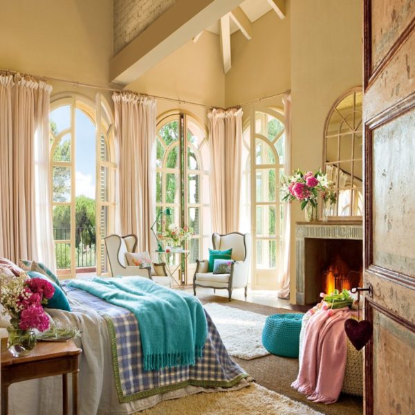 A cozy bedroom with an arched window and a fireplace.