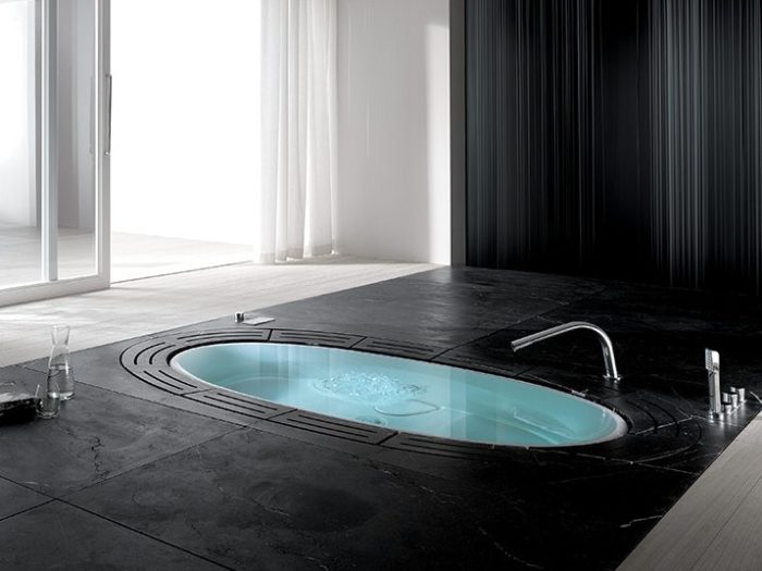 A stylish bathtub in a black bathroom with a tiled floor.