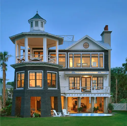 A black and white lighthouse home with a pool and deck.