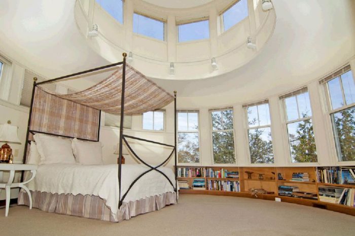 A cozy lighthouse home with a circular bed and bookshelves.
