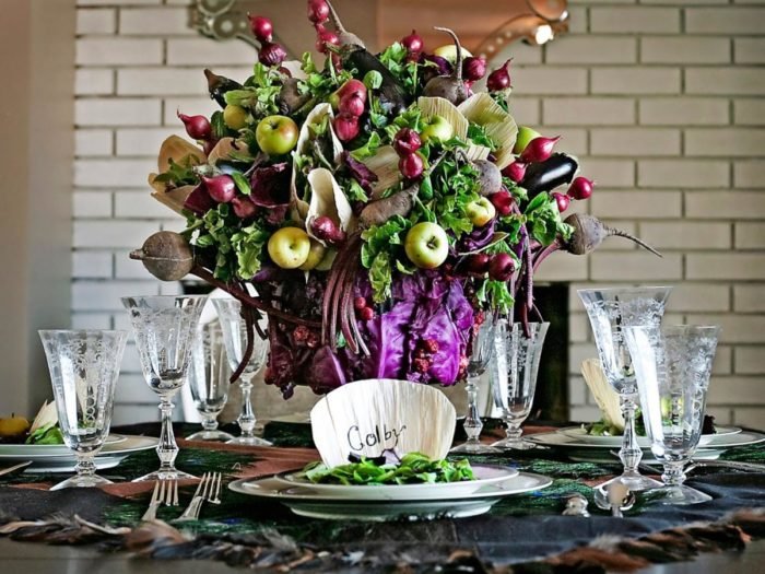 A fresh table setting adorned with a large arrangement of greens and purples.