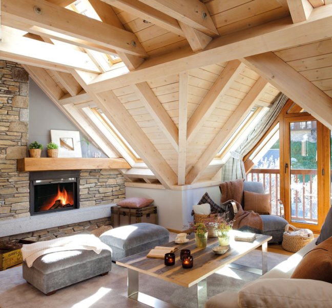 A cozy living room with a stone fireplace and wooden beams.