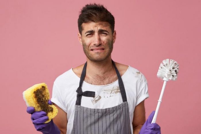 A man performing home maintenance tasks with a sponge and a mop.