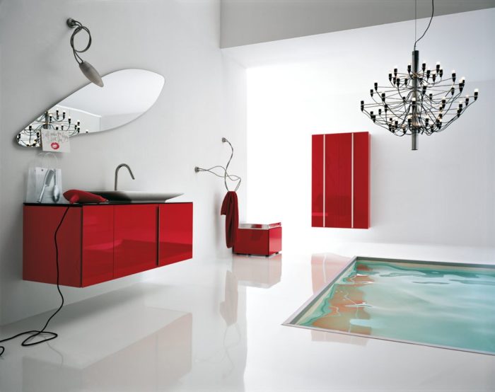 A stylish bathroom with red cabinets and a chandelier.