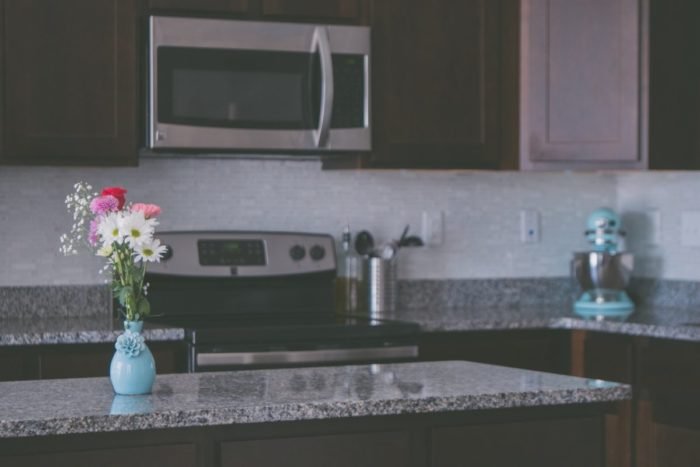 A kitchen with brown cabinets and a vase of flowers, featuring a kitchen island.