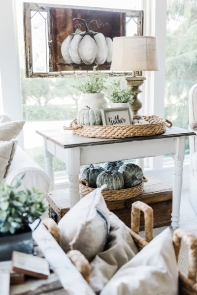 A living room with fresh fall decorating, featuring a white couch and wicker baskets.