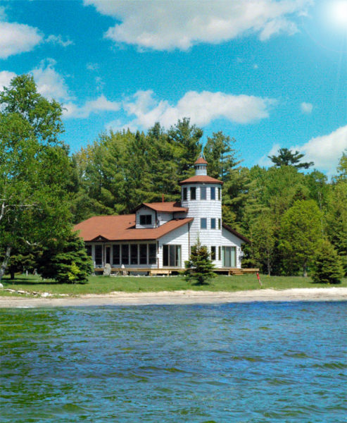 A home resembling a lighthouse sits on the shore of a lake.