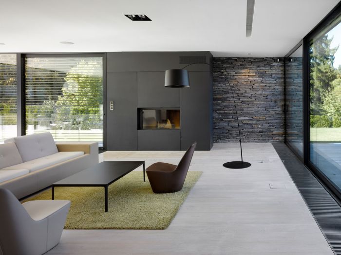 A modern living room with a fireplace and large windows featuring a minimalist approach.