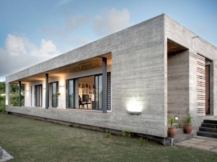 A modern precast concrete house in the middle of a grassy area.